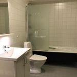 badrum med kombinerat bad / dusch, duschdörr, handfat, toalett, spegel, och sminkbord