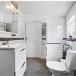 half bath with tile flooring, toilet, vanity with extensive cabinet space, and mirror