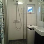 badrum med klinkergolv, bricka / torktumlare, sminkbord, dusch, och handfat