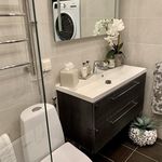 badrum med bricka / torktumlare, spegel, handfat, toalett, och sminkbord