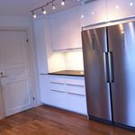 kök med rostfritt stå, parkettgolv, kylskåp, vita skåp, och mörkt golv