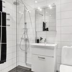 badrum med klinkergolv, dusch, handfat, toalett, spegel, och sminkbord