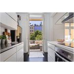 kitchen with natural light, oven, range hood, electric stovetop, light flooring, light countertops, and white cabinetry