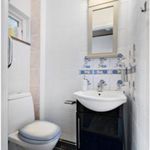 badrum med klinkergolv, spegel, sminkbord, handfat, och toalett