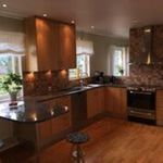 kitchen with natural light, extractor fan, dark countertops, dark hardwood flooring, and brown cabinetry